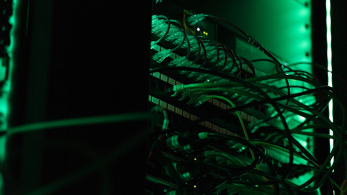 Intense green light illuminates a server rack dense with connected network cables, representing the robust infrastructure of Canadian web hosting.