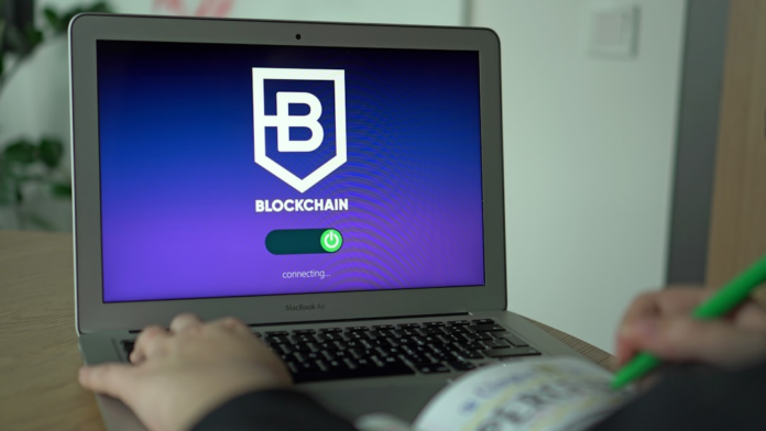 Hands interact with a laptop displaying a Blockchain connection screen, alongside a hand taking notes with a green pen, representing focused digital analysis for ecommerce and conversion optimization.