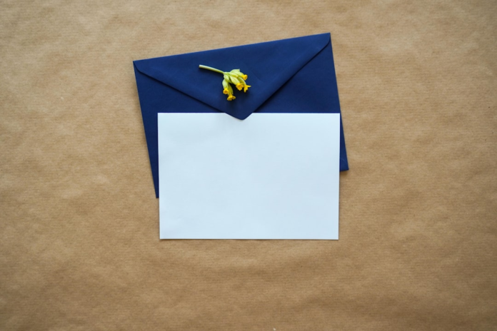 Blank white card emerging from a navy blue envelope with a yellow flower, representing effective, personalized email marketing to boost sales.