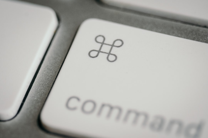 Close-up of a white computer keyboard's command key, featuring the loop symbol and command text, signifying keyboard shortcuts for efficient digital content creation.