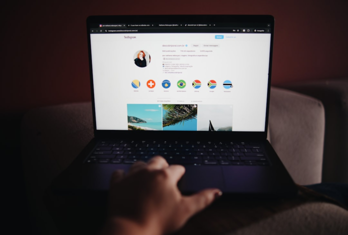 A person's hand operates a laptop showcasing an Instagram profile with vibrant travel content, symbolizing the role of social media in driving online engagement and ecommerce traffic.