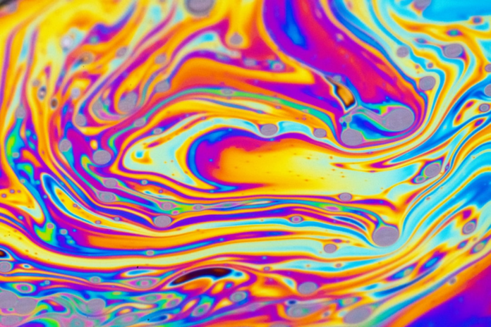 Vibrant, swirling iridescent patterns in shades of yellow, orange, blue, and purple capture the dynamic, intelligent flow of data and innovation in modern marketing automation.