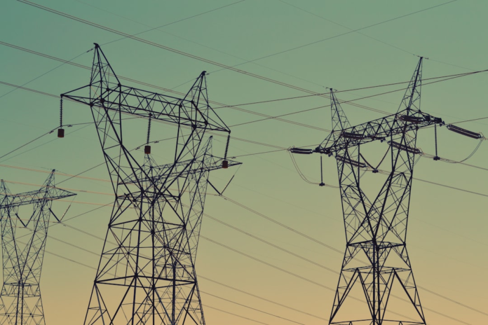 Interconnected power lines stretch between large transmission towers silhouetted against a vibrant gradient sky, symbolizing the robust integration and powerful connectivity of Odoo marketing automation with tools like Mautic and HubSpot.