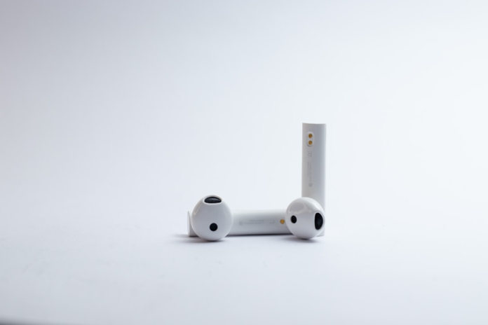 Sleek white wireless earbuds and their charging case are neatly displayed on a minimalist white background, symbolizing modern communication and efficient tools beneficial for open source CRM software users.