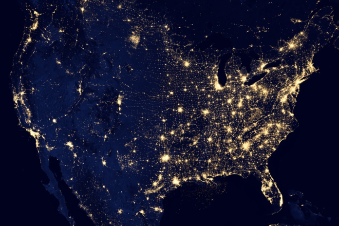 Sweeping nighttime satellite view of the United States with glowing city lights, symbolizing the vast, interconnected network optimized by Salesforce OMS for efficient order management.