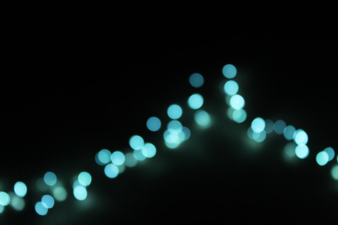 A flowing stream of ethereal blue and teal bokeh lights illuminates a dark background, representing seamless marketing automation integration.
