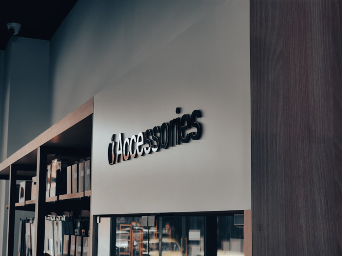 Prominent 3D 'iAccessories' store sign on a light wall, next to shelves stocked with products, in a sleek modern retail environment ideal for a Shopify website.